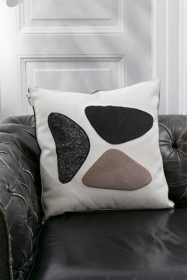 Minimalistic throw pillow on a black sofa creating with faux furr stitching ontop to give it an elegant decoration style