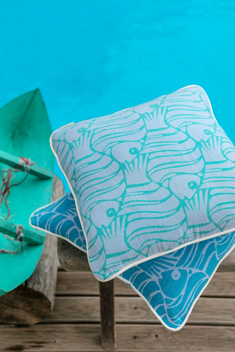 blue throw pillow with fish pattern next to the sea